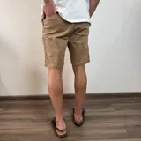 Bermuda color beige claro, estilo chino, confeccionada en gabardina. Presenta un corte recto y dobladillo en el ruedo.