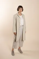 Camisa larga color crema con rayas verticales finas en gris, con botones dorados y bolsillo plaque en la delantera.