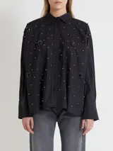 Camisa de algodón negra con detalles de pedrería y diseño holgado en manga larga.