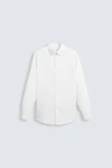 Camisa blanca de manga larga con cuello italiano y corte slim fit. Presenta cierre frontal de botonadura y puños con botón.