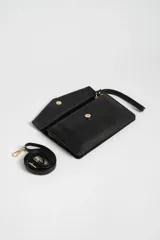 Bandolera negra de cuero sintético con solapa y correa larga ajustable.