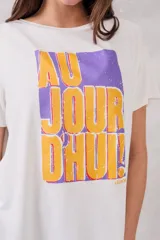 Remera blanca de corte holgado con estampado frontal de un recuadro violeta con la frase "Au jour d'hui!" en letras color naranja.