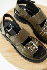 Sandalias de cuero color verde oliva con suela track y hebillas plateadas.