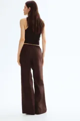 Pantalón marrón de algodón, corte holgado, tiro alto, cintura elástica fruncida con cordón ajustable, piernas anchas y bolsillos laterales.