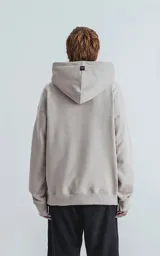 Hoodie color arena de frisa premium, con capucha gigante ajustable y puños elastizados.