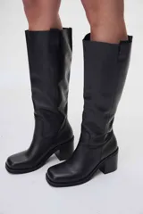 Bota de cuero negra, de caña alta y taco cuadrado.
