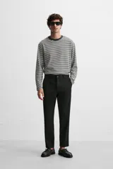 Pantalón slim fit negro confeccionado en tejido con elasticidad en ambas direcciones. Cuenta con bolsillos frontales y traseros de vivo con botón. Cierre frontal con cremallera y botón.