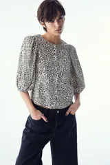 Blusa de tejido liviano con estampado de leopardo en blanco y negro. Modelo entallado con cuello redondo, cierre de botones y mangas globo tres cuartos con puños elásticos.