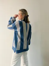 Sweater tejido a rayas horizontales anchas en color celeste y blanco, con sutil brillo. Diseño amplio y cómodo.