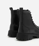 Bota de caña media color negro, estilo coturno, con cordones y cierre lateral. Suela track.