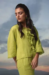 Blusa color crema de lino con mangas abullonadas y lazos frontales.