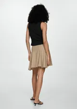 Blusa negra sin mangas con cuello camisero y cierre de lazos en la parte delantera.