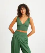 Blusa cropped color verde bosque, con escote en V profundo, tirantes dobles finos y estructura tipo corsé con costuras verticales en el frente.