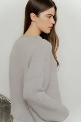 Sweater de punto color gris claro, de corte holgado y mangas largas.