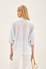 Camisa blanca de voile con rayas finas, corte amplio, cartera con botones y bordado de flores en el frente.