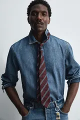 Camisa relaxed fit confeccionada en denim de algodón con cuello solapa, manga larga con puño abotonado, efecto lavado medio y cierre frontal con botones.