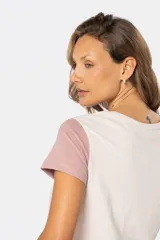 Remera de manga corta y cuello redondo, con bloque de color: cuerpo color crema, manga derecha color rosa y manga izquierda color celeste.