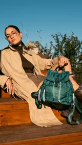 Mochila verde militar de nylon con tapa y broche metálico. Tiene apertura superior con cierre marinero, bolsillos internos, bolsillo con cierre metálico al frente y laterales. Incluye asas rígidas de mano y correas regulables para colgar en la espalda.