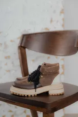 Botas de caña baja color marrón con cordones negros, suela track color beige y detalles en cuero.