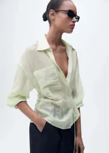 Camisa color verde agua semitransparente con cierre de lazo en la cintura, diseño cruzado, bolsillo de parche en el pecho, cuello camisero y mangas largas.