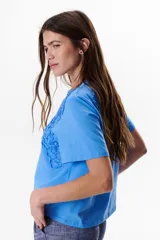 Remera blanca de manga corta con detalle de encaje floral en el hombro.