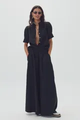 Pantalón negro súper ancho de lino 100% natural, tiro medio-alto, con tablas delanteras, elástico en la parte trasera y bolsillos laterales.