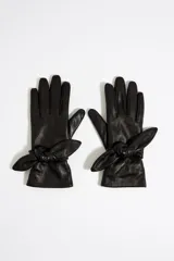 Guantes de piel color naranja con detalle de lazo en la muñeca.