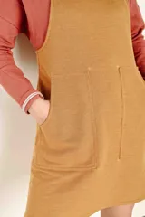 Vestido jumper color ocre, de corte recto, con breteles anchos y bolsillos frontales.