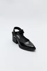Zapato negro tipo zueco con acabado charol, tira ancha con hebilla metálica y taco ancho de altura media.