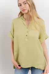 Blusa blanca de lino con escote en V abotonado y mangas cortas arremangadas.