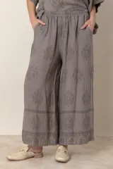 Pantalón palazzo gris con estampado floral al tono, cintura elastizada y bolsillos laterales.