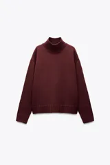 Jersey de punto color borgoña, con cuello alto y mangas largas. Tiene aberturas laterales en el bajo y terminaciones acanaladas.