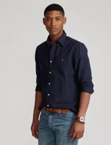 Camisa de vestir azul marino, corte regular, cuello button-down, manga larga y logo bordado en rojo en el pecho.