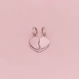 Dije de plata 925 con forma de corazón partido en dos mitades, cada una con un aro para colgar.