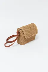 Cartera tipo bandolera de paja color beige con correa de cuero marrón ajustable.