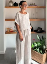 Pantalón ancho de tiro alto, color beige claro con textura, confeccionado en tela crepé. Presenta cintura elástica con cordón ajustable.