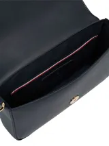 Cartera cruzada de mujer color azul marino, de material sintético liso, con solapa frontal y herrajes metálicos dorados. Presenta un monograma TH en el centro de la solapa y un charm colgante con el logo TH en el lateral.