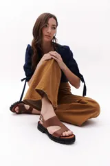 Sandalias marrones de cuero con suela track negra y hebilla plateada.