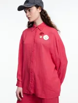 Camisa celeste de calce relajado con abertura en la espalda y mangas largas. Confeccionada en tejido liviano de lino y viscosa. Incluye tres pins decorativos.