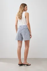 Bermuda de tiro alto con estampado de rayas verticales azules y blancas, con bolsillos laterales y cierre frontal con botón y cremallera.