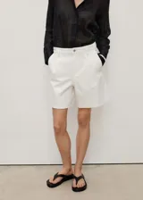 Short blanco de tiro medio con cierre de cremallera y botón, bolsillos laterales y pinzas delanteras. Confeccionado en tejido de algodón estilo tejano vaquero.