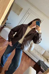 Campera bomber de cuero color vino, con cuello de piel sintética desmontable y corte oversized.