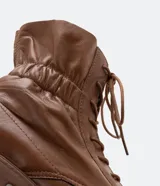 Bota de cuero color marrón con cordones, caña media con detalle de elástico en la parte trasera, taco bloque medio y suela track.