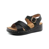 Sandalia de cuero sintético color negro, con plataforma baja y tiras cruzadas en el empeine. Ajuste con hebilla dorada al tobillo.