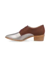 Zapato acordonado de cuero color plateado con puntera fina y detalle de cuero marrón en el talón.