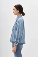 Camisa de denim celeste con bordados geométricos en el frente, corte recto, cuello camisero, manga larga con frunces en los hombros y puños abotonados.