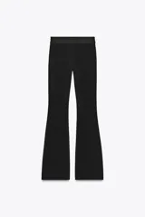 Pantalón negro de tiro medio, confeccionado en tejido elástico con cintura elastizada y corte acampanado.