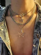 Set de tres collares plateados de diferentes largos. El primero es una gargantilla con cierre de gancho y dije de estrella con borde rojo. El segundo es un collar de cadena gruesa con dije de estrella calada. El tercero es un collar de cadena fina con dije de estrella calada.