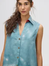 Vestido camisero midi sin mangas confeccionado en viscosa con un patrón desteñido en tonos azul y blanco. Posee cuello camisero, cierre frontal con botones y un calce holgado.