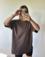 Remerón de manga corta color marrón oscuro, con cuello redondo y corte holgado (oversize).
